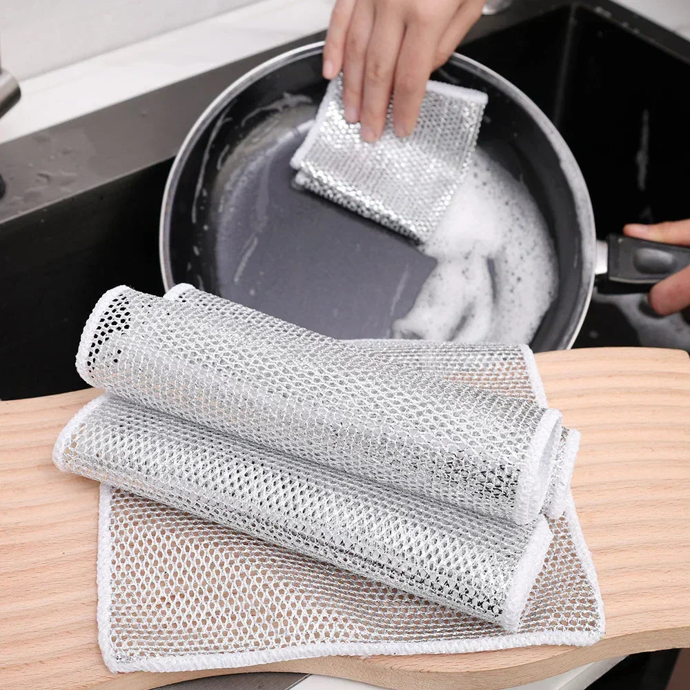 ScrubPad reinigt eine fettige Pfanne, daneben gefaltete Ersatztücher